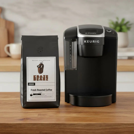 Black Uganda pods coffee bag with a label and Kraze Beanz logo with a Kerig on kitchen counter home backround